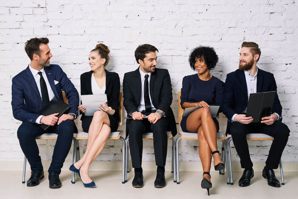 A group of salespeople sitting in chairs and talking to each other