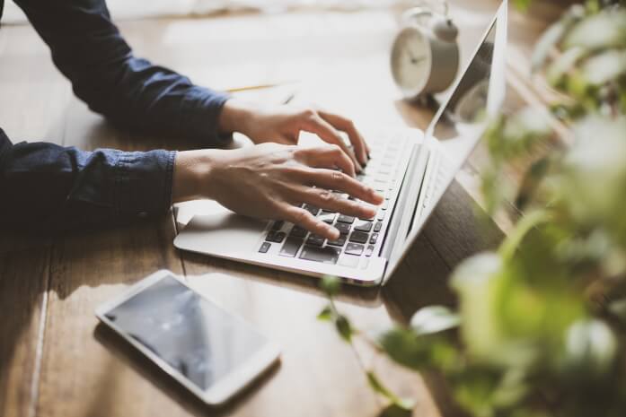 Person using a laptop and phone on a desk