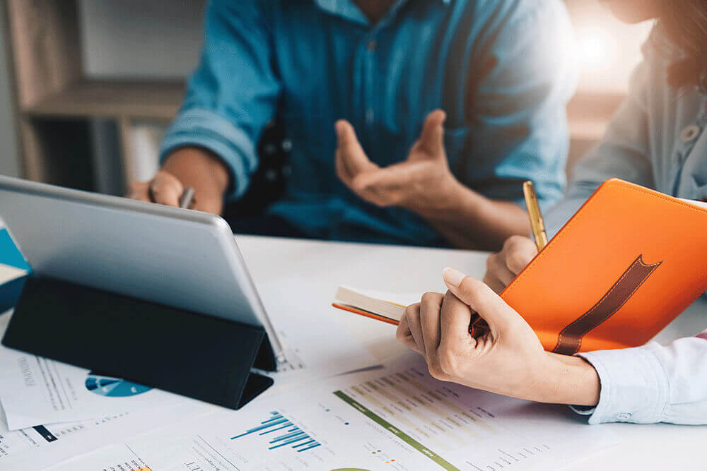 Salespeople at a desk having a discussion with reports